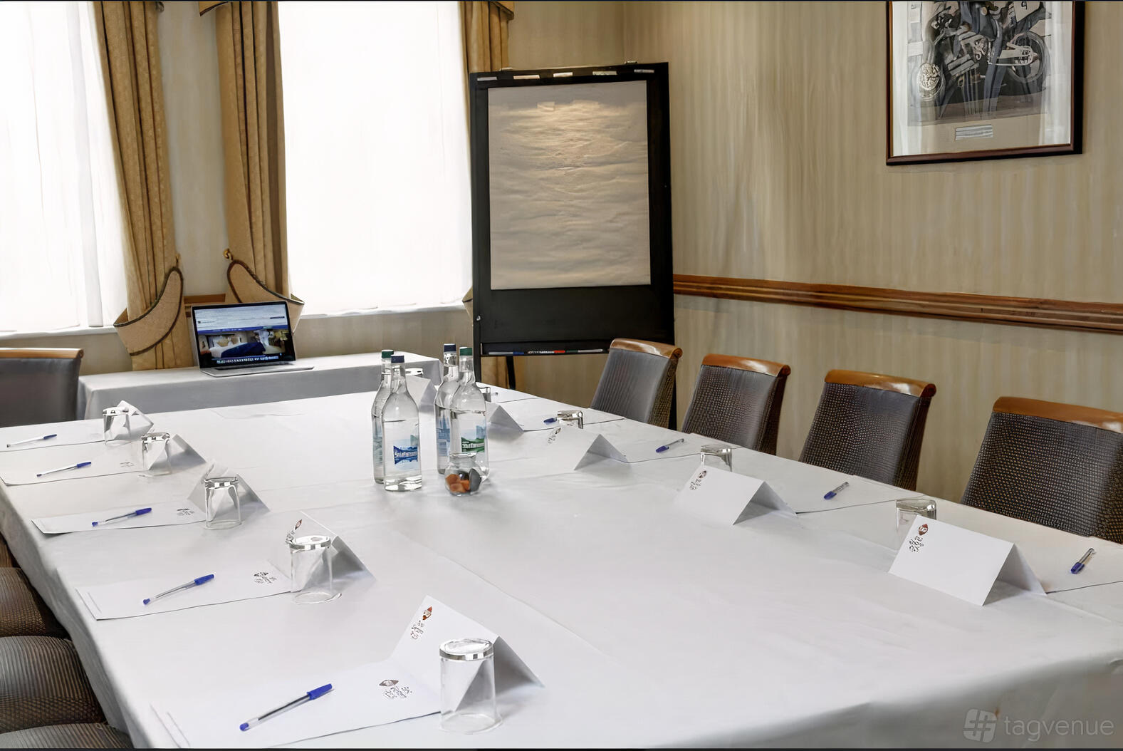 A hotel meeting room with a boardroom table, bottled water, notepads, and natural light at Best Western Plus Manor Hotel.