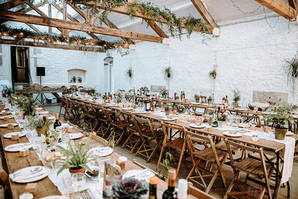 A gallery with long wooden tables, greenery centerpieces, exposed beams, and natural light at Silk Mill Studios & Gallery.