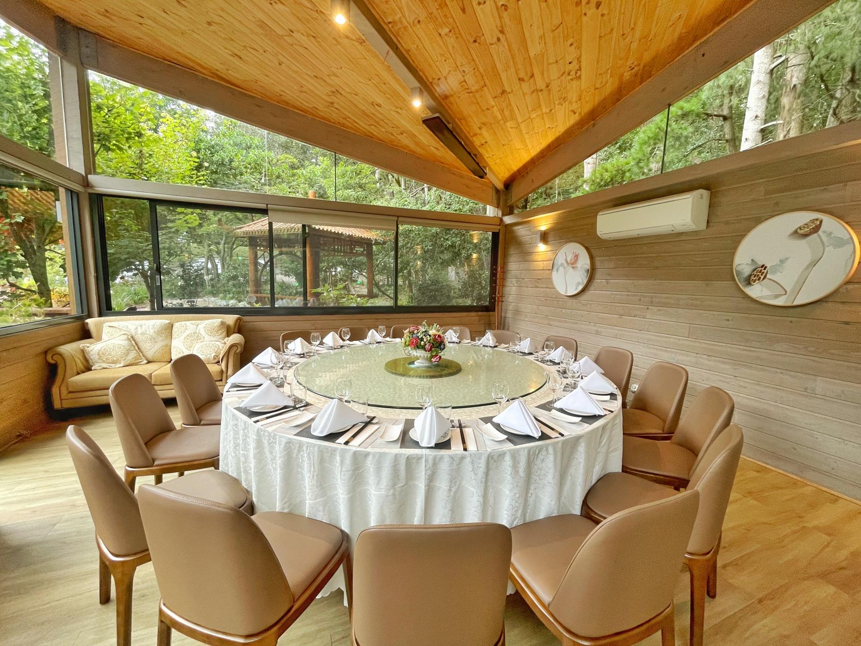 A dining room with large windows, a round table with a glass lazy Susan, and leather chairs at Olinda Tea House.