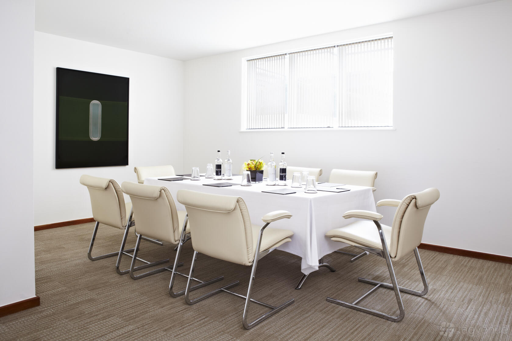 A lounge with cream leather chairs, a square table with white linen, and large window at COMO Metropolitan London.