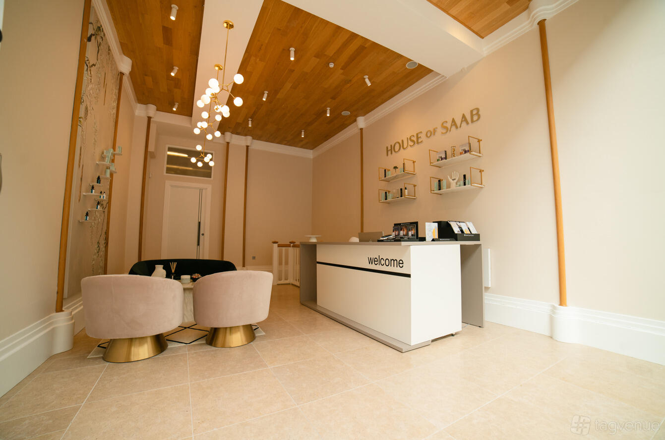 An event venue with wood panel ceiling, chandelier lighting, reception desk, and velvet seating at House of Saab.