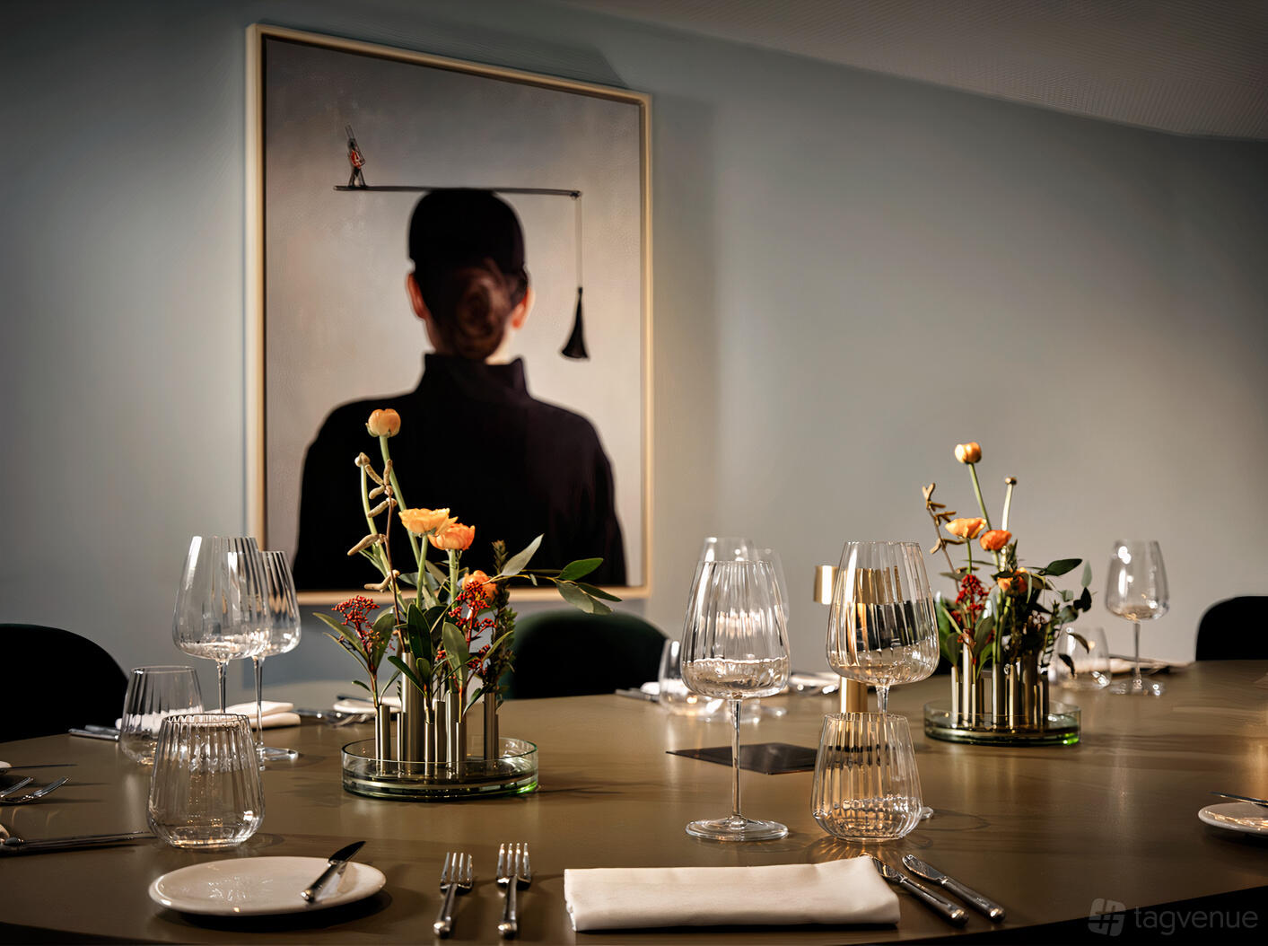 An event space in a hotel with a long table, floral centerpieces, glassware, and modern art at art'otel London Battersea Power Station.