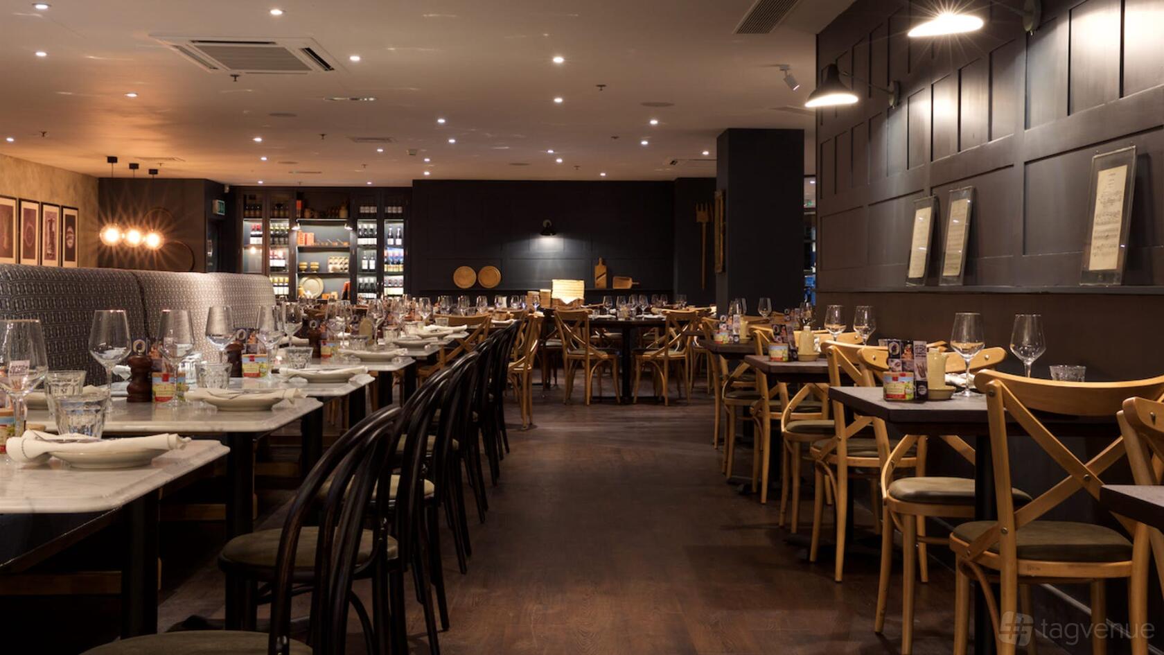A restaurant dining area with wooden floors, marble tables, and set glassware at Brasserie Blanc Southbank.