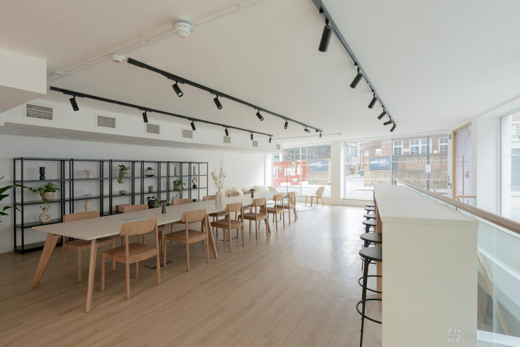 A coworking meeting room with long wooden tables, light wood chairs, and floor-to-ceiling windows at WorkPad: 4 Garrett Street.