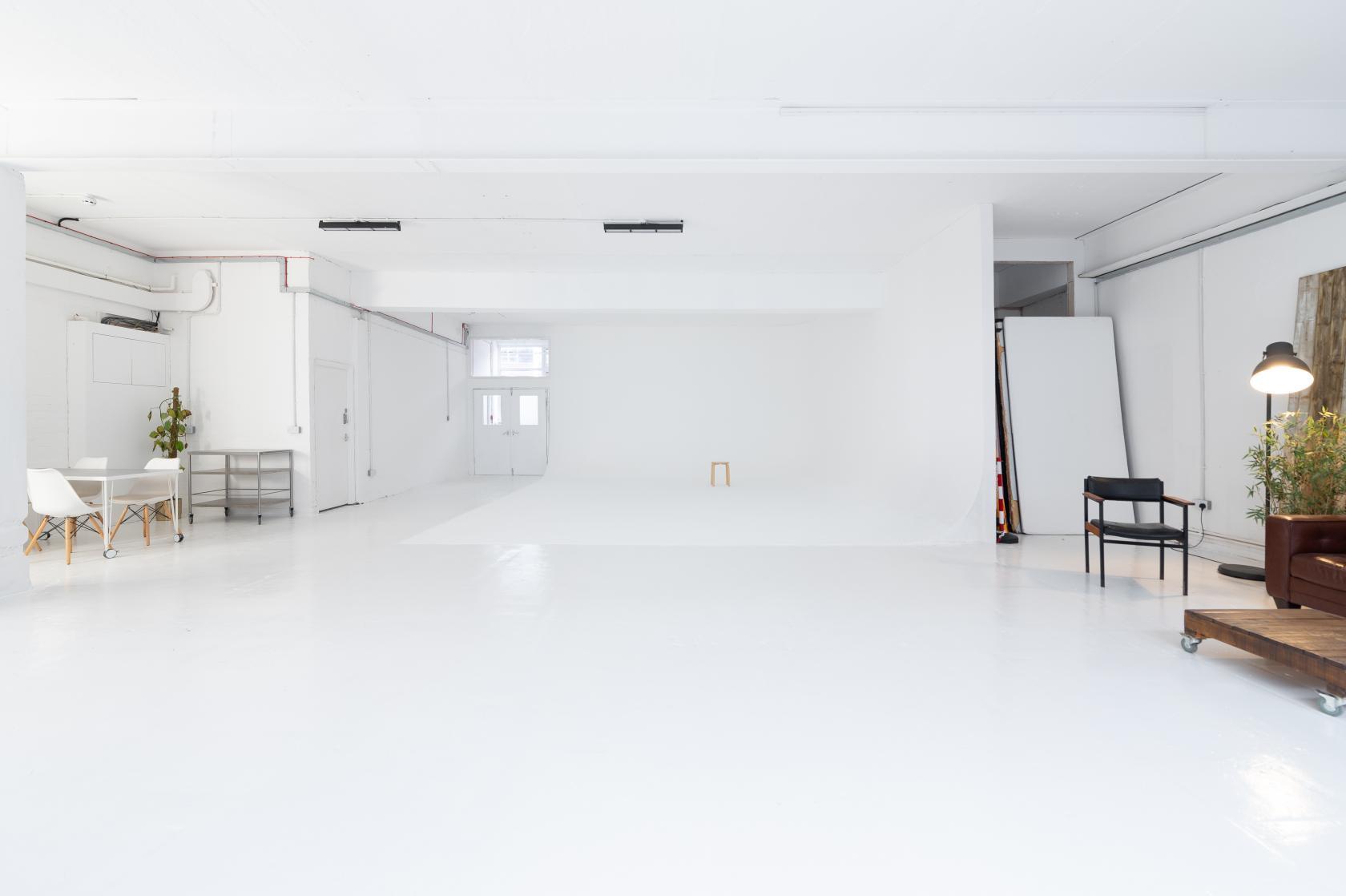A photo studio with white floors, seamless white walls, and minimal furniture at 69 drops studios.