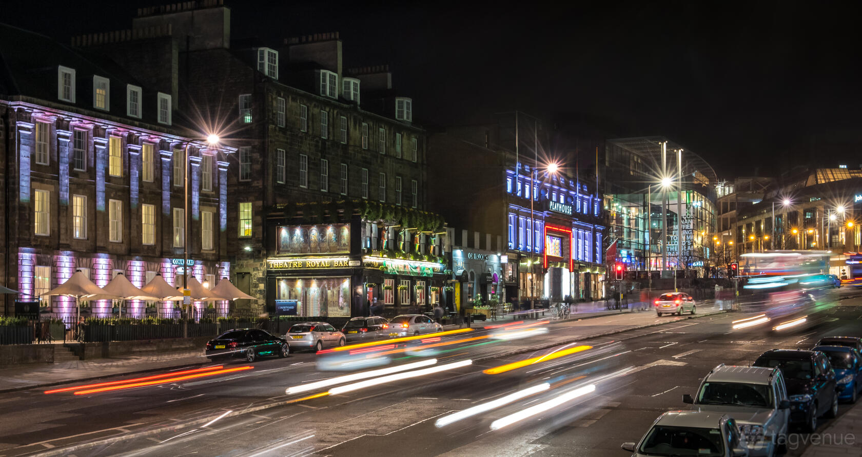 A city street at night with illuminated building facades and light trails from passing cars outside Courtyard by Marriott Edinburgh.