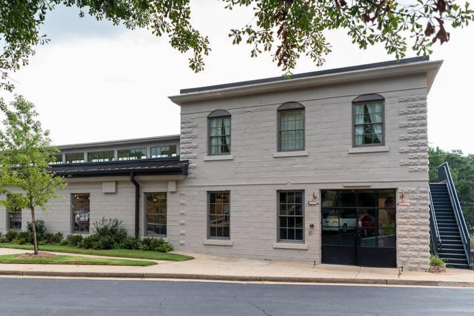 A versatile event space with light-colored brick exterior, large windows, and landscaped entry at Upstairs Atlanta.