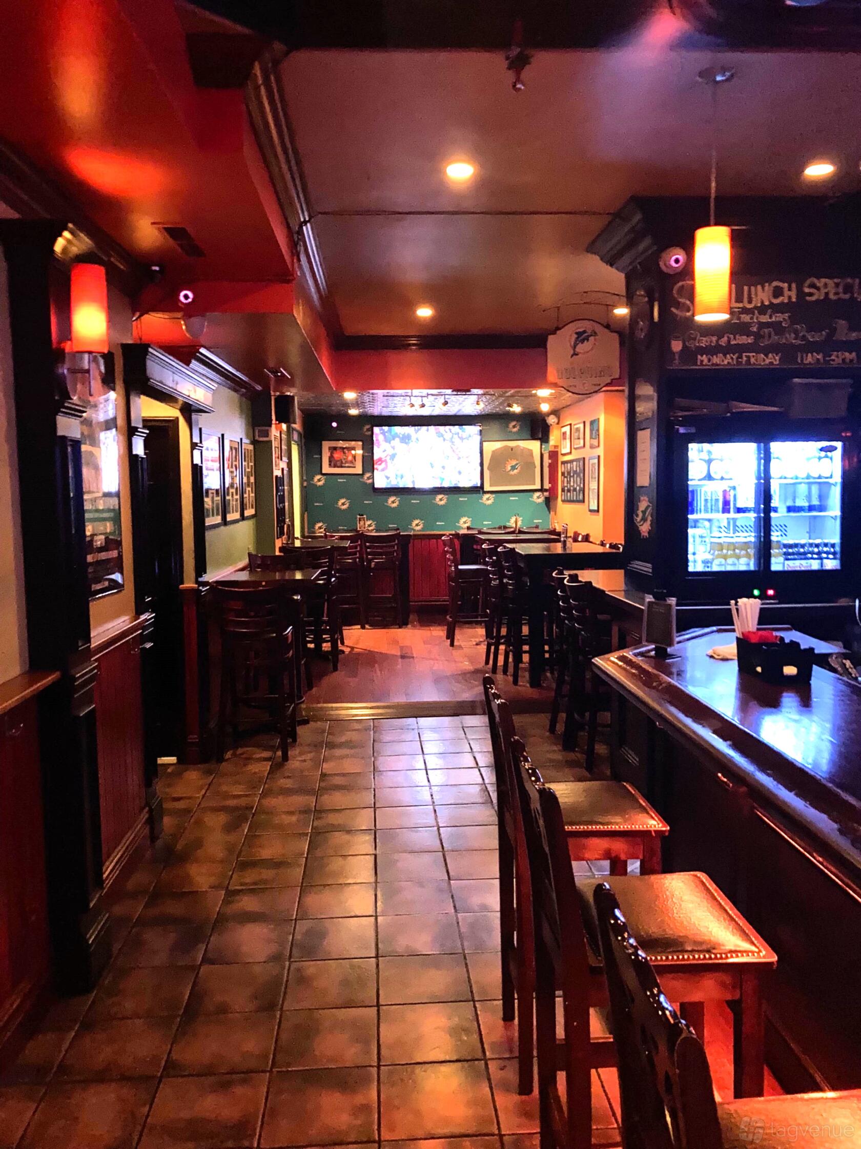 An event space in a bar with high-top tables, wall-mounted sports memorabilia, and a large TV at Slattery's Mid Town Pub.