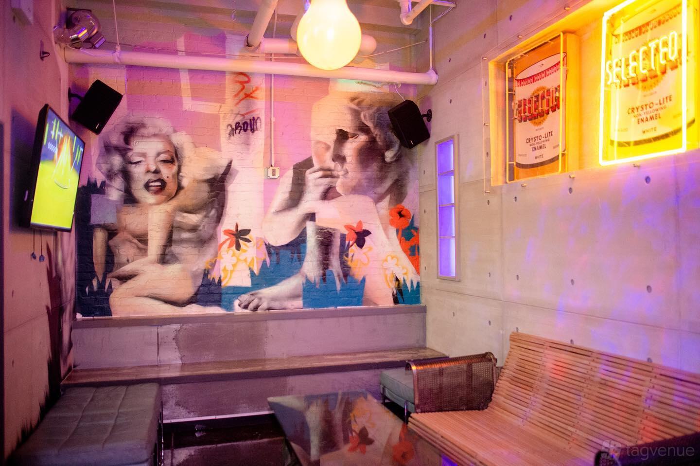 An event venue with colorful mural walls, tufted benches, and neon signs in The Painters Room at RPM Underground.