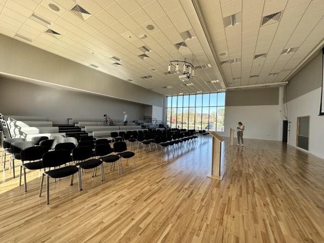 A school hall with tiered seating, rows of black chairs, and floor-to-ceiling windows at Seashell.
