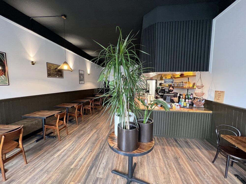 An event space in a restaurant with wooden tables, modern lighting, and potted plants at Aman Cafe.