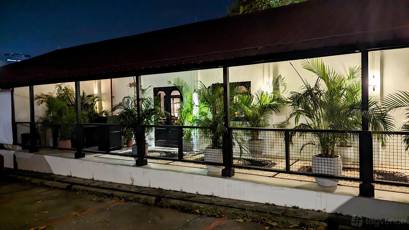 A restaurant exterior with potted palm plants, white walls, and a covered walkway at Ce Soir Restaurant.