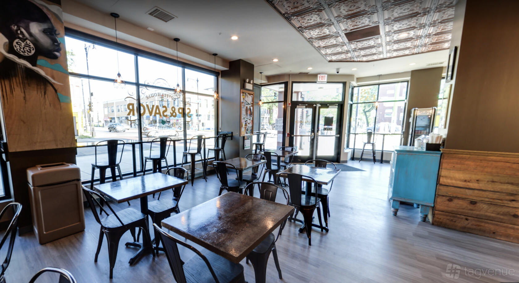 A cafe with metal chairs, wooden tables, large windows, and patterned tin ceiling at Sip & Savor - The Rosenwald.
