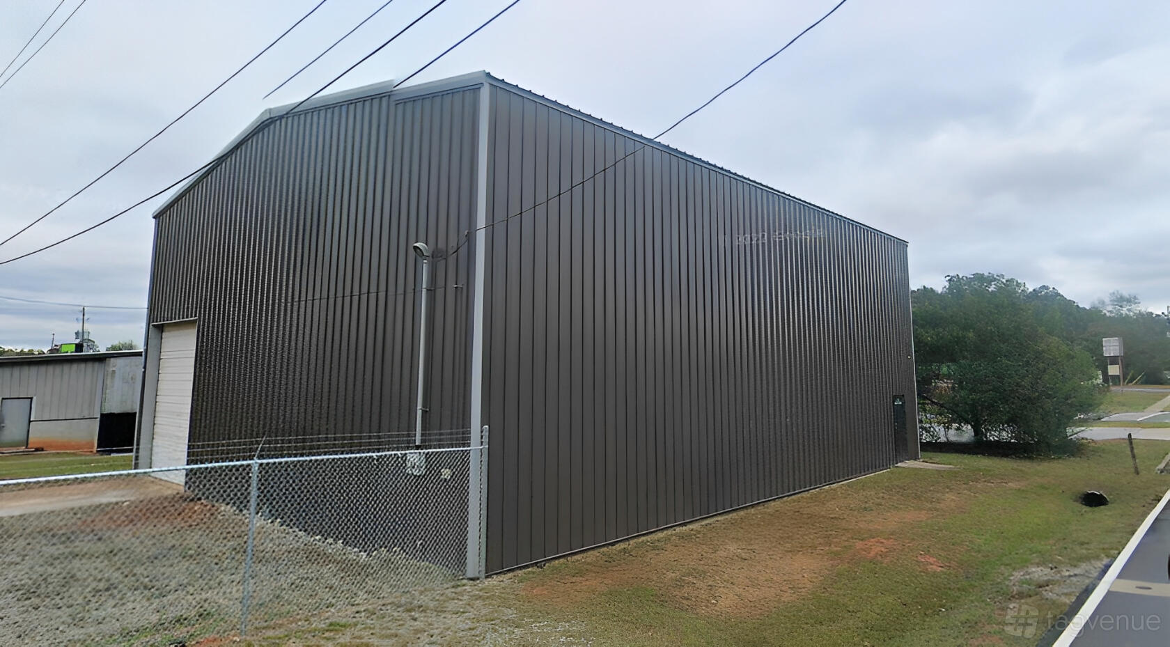 A dark gray warehouse with metal siding and a roll-up garage door at Luna’s Cove Events & Designs.