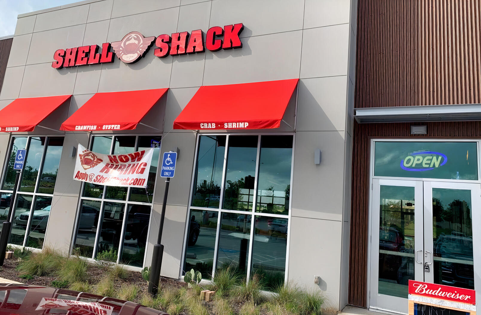 A restaurant exterior with red awnings, large windows, and glass entrance doors at Shell Shack Forth Worth.