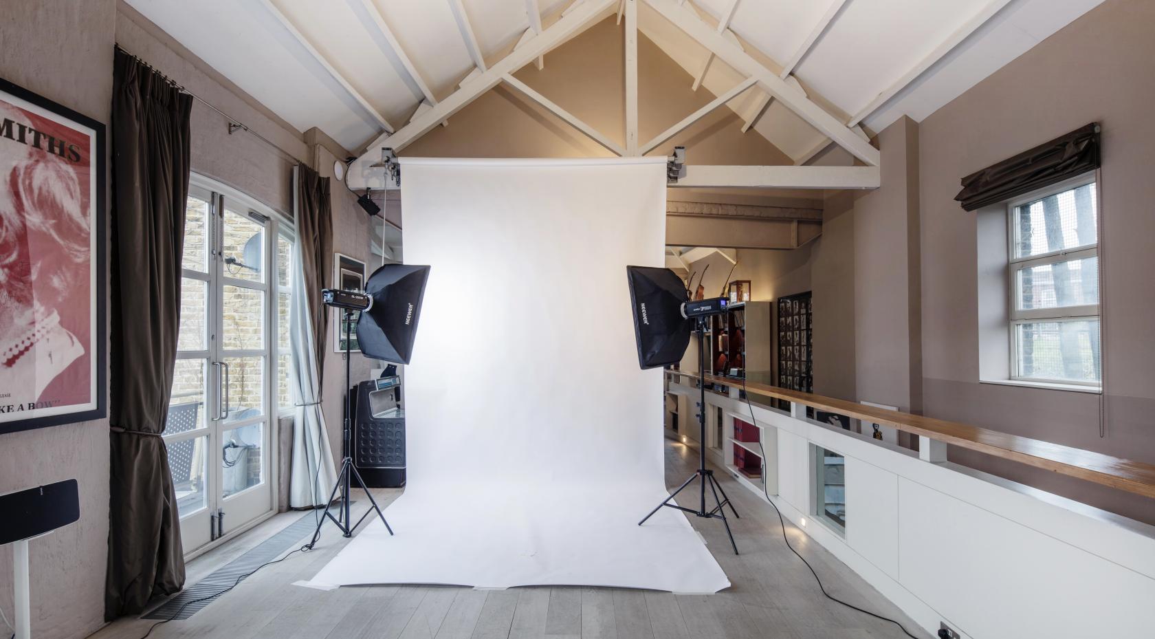 A photo studio with a white backdrop, softbox lights, high vaulted ceiling, and large windows at I AM LONDON.
