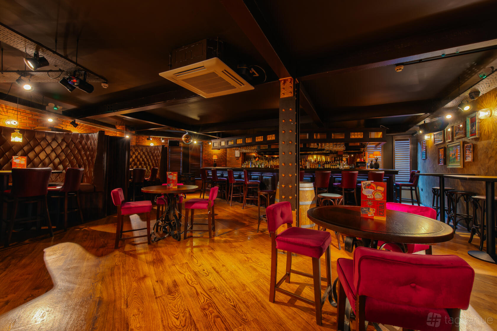 An event space in a restaurant with wood floors, red upholstered chairs, and a long bar at Revolucion de Cuba Leeds.