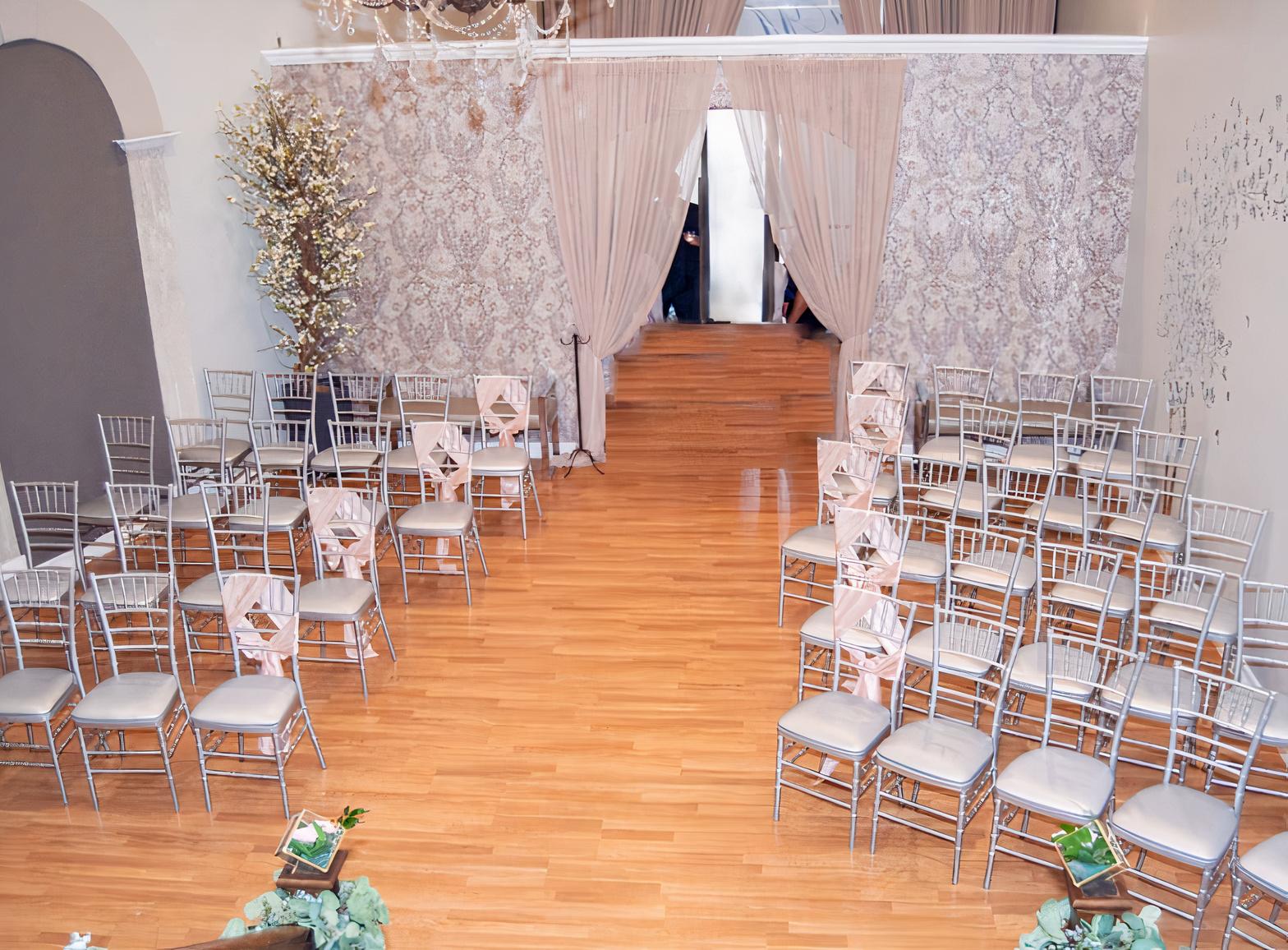 An event venue with silver chairs, wood floors, and floral wallpaper at Venue At Memorial.