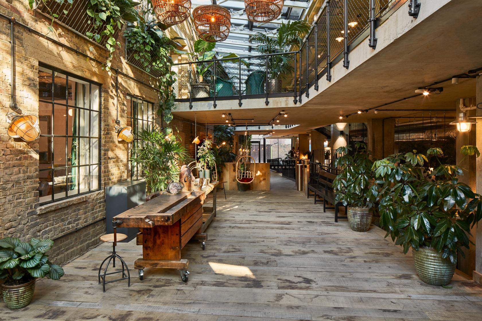 A coworking meeting room with exposed brick walls, skylights, and indoor plants at The Fisheries.