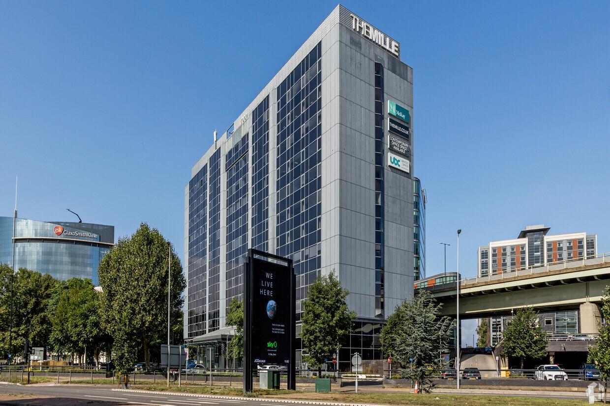 A modern meeting centre in a tall glass building with large signage and surrounding greenery at UBCUK Brentford The Mille.
