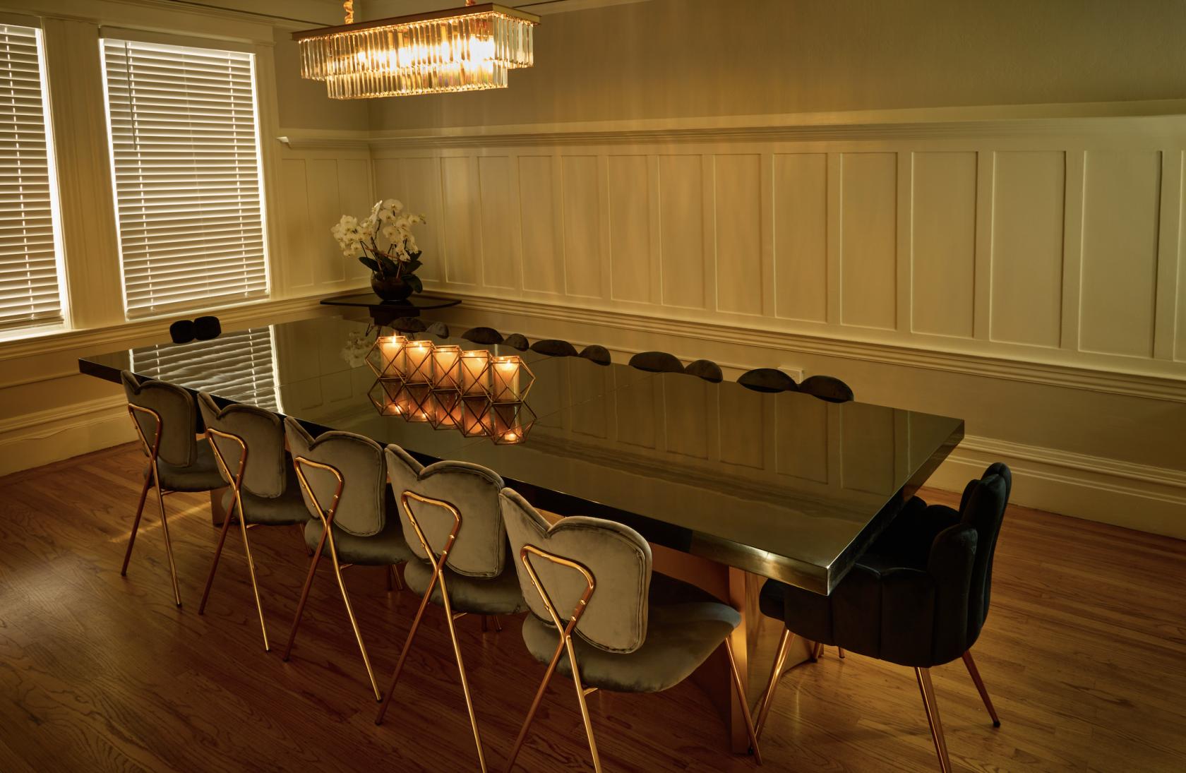 An intimate event space with a long mirrored table, velvet chairs, and a modern chandelier at Movida.