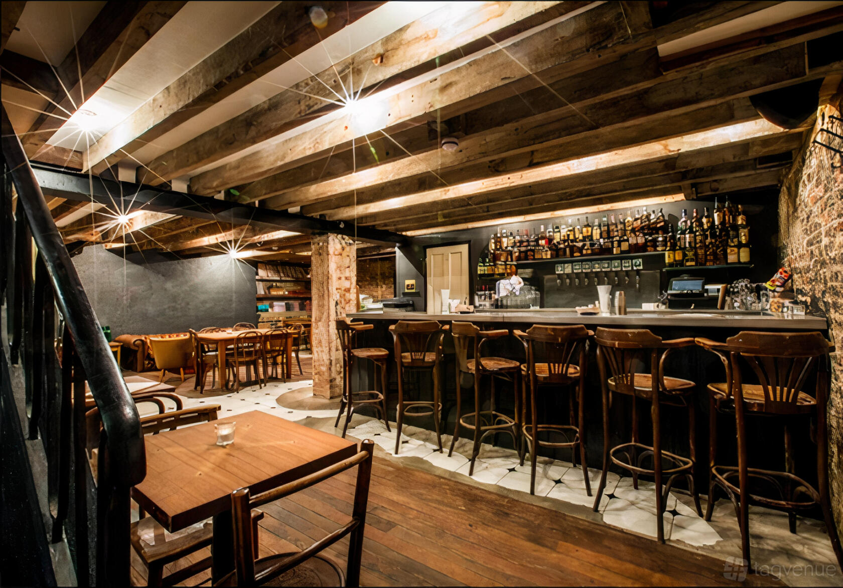 A basement bar with exposed wooden beams, brick walls, and a stocked counter with bar stools at The Gallery.