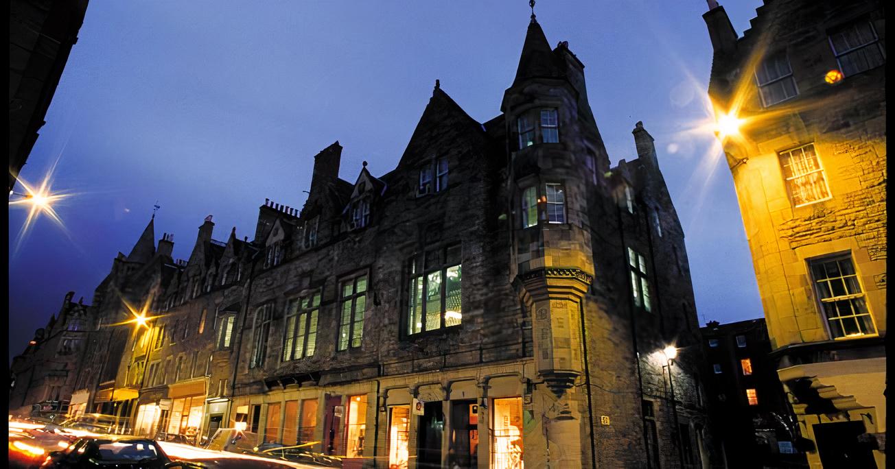 A stone meeting centre with large pointed windows and historic façade lit by streetlights at Edinburgh Training and Conference Venue.