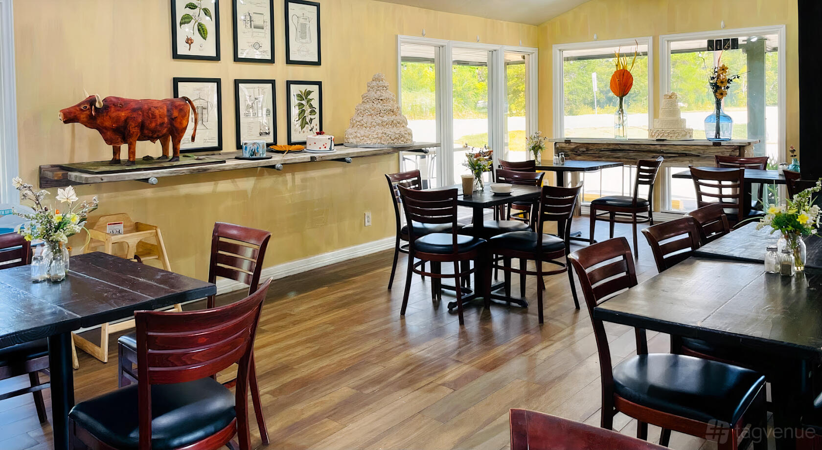 A cafe with wood floors, dark wooden chairs, wall art, and large windows at Rustika Cafe and Bakery: Friendswood.