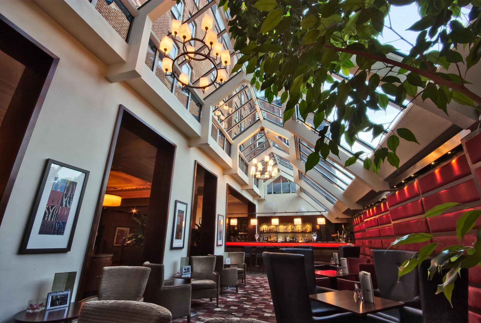 A function room with a glass ceiling, red cushioned walls, and a bar area at The Rembrandt Hotel