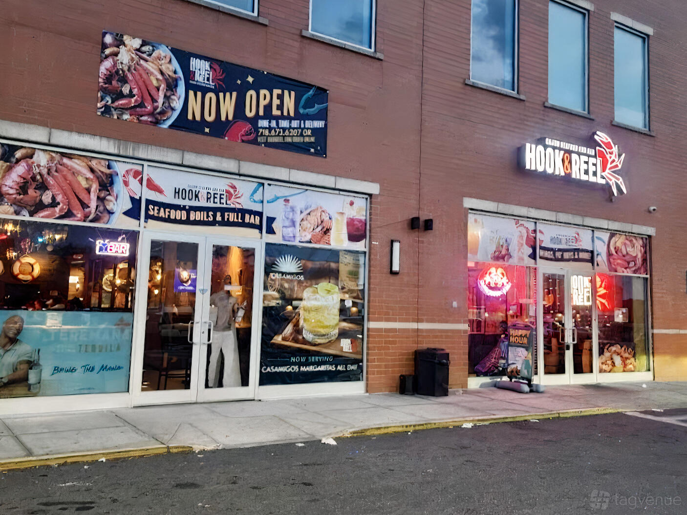 A restaurant with large glass windows, seafood signage, and neon lights at Hook & Reel- Howard Beach.
