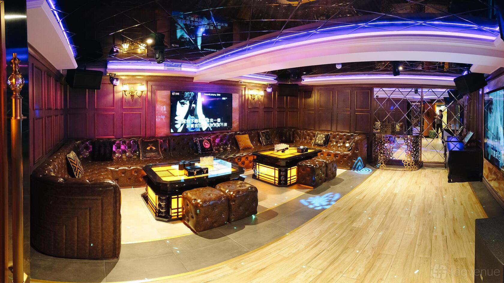 A private event space with leather tufted sofas, a large TV screen, and ambient lighting at Sugar karaoke.