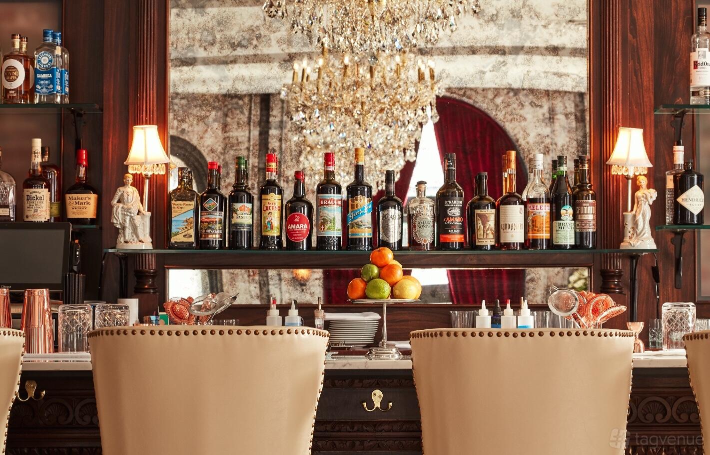 A restaurant lounge bar with an ornate chandelier, mirrored wall, and a display of spirits at Cicala at The Divine Lorraine.