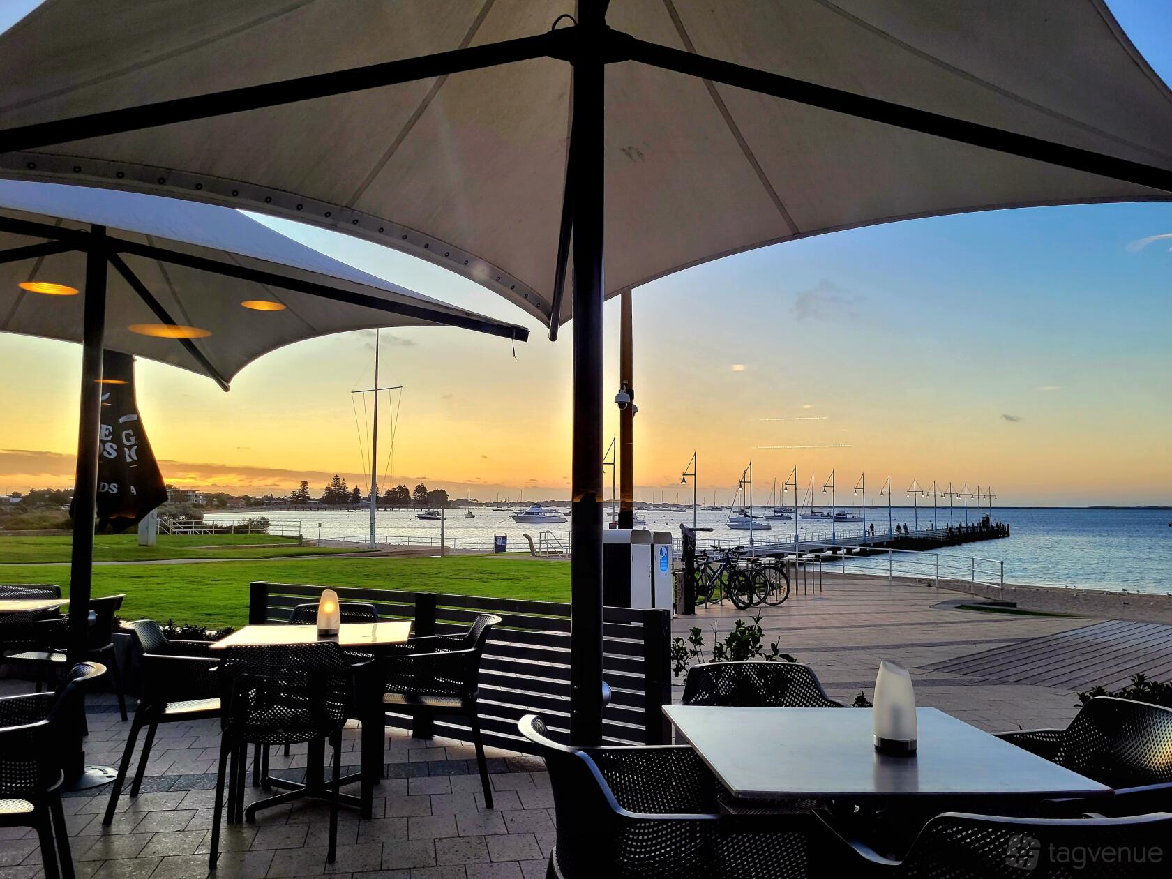 An outdoor restaurant space with waterfront views, patio tables, and large umbrellas at Latitude 32.