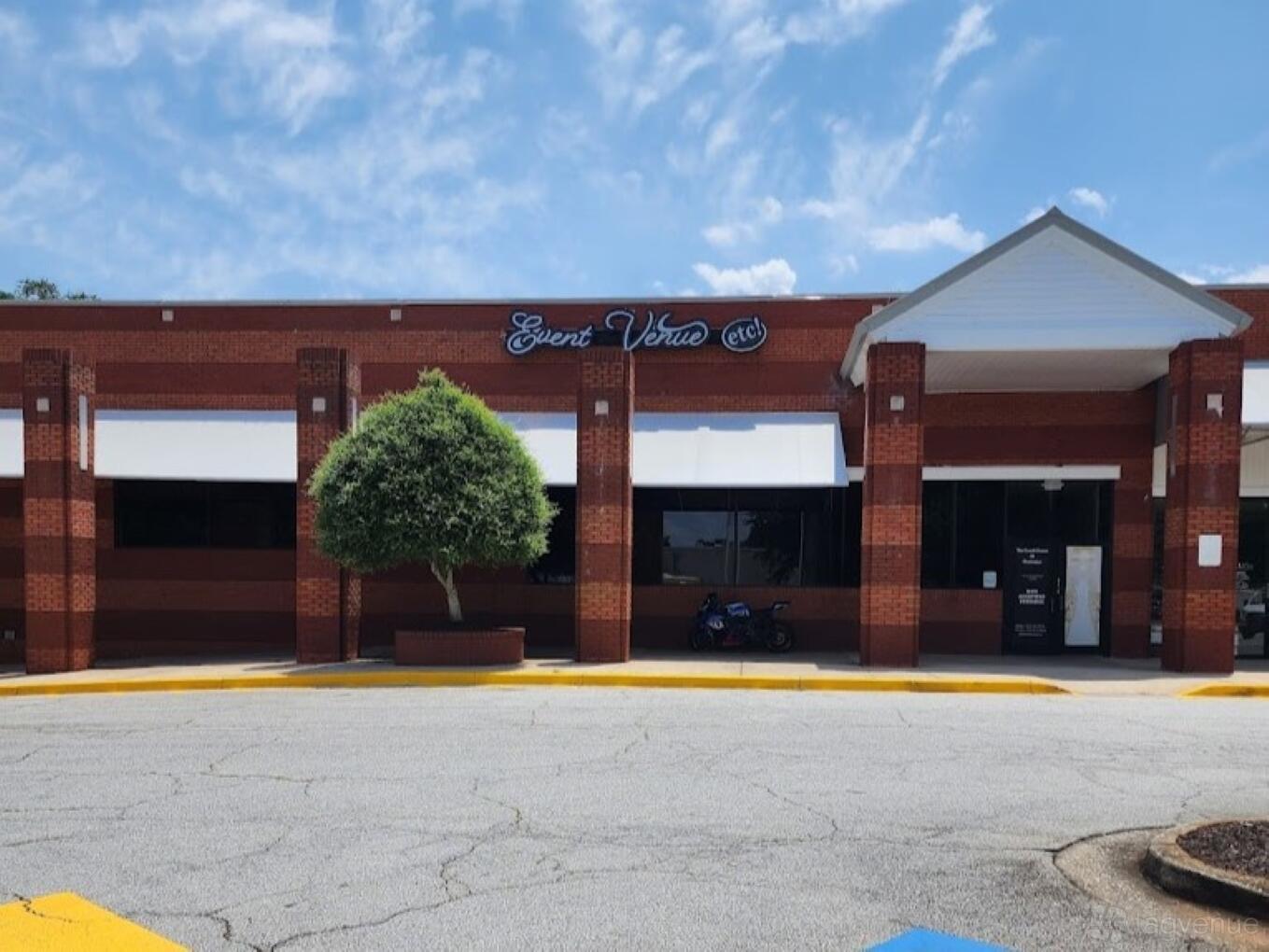 A versatile event space with red brick exterior, white awnings, and a decorative tree at The Event Venue at Classique.