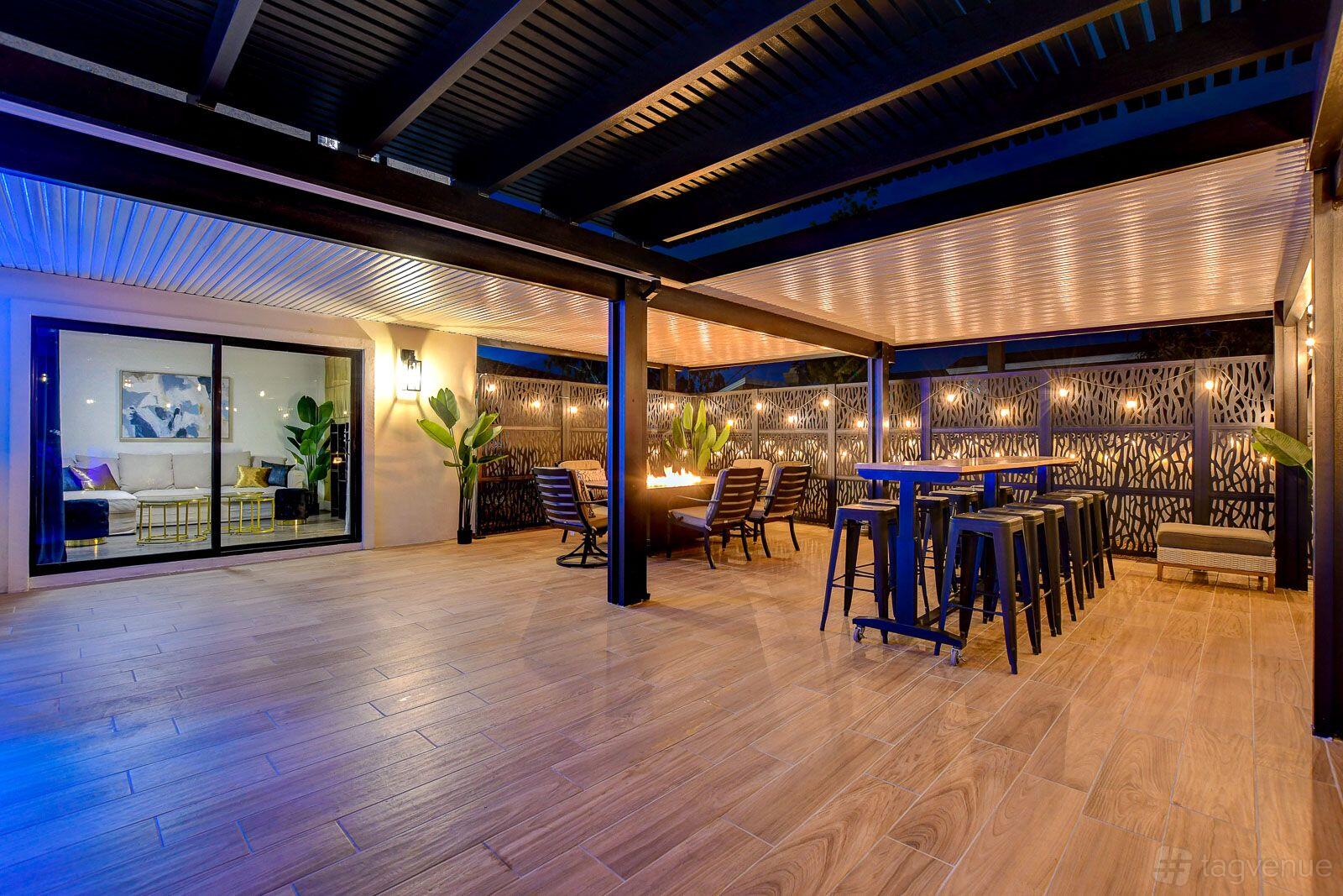 An event venue with covered wooden flooring, lounge chairs, high tables, and decorative lighting at Beach Resort Las Vegas.