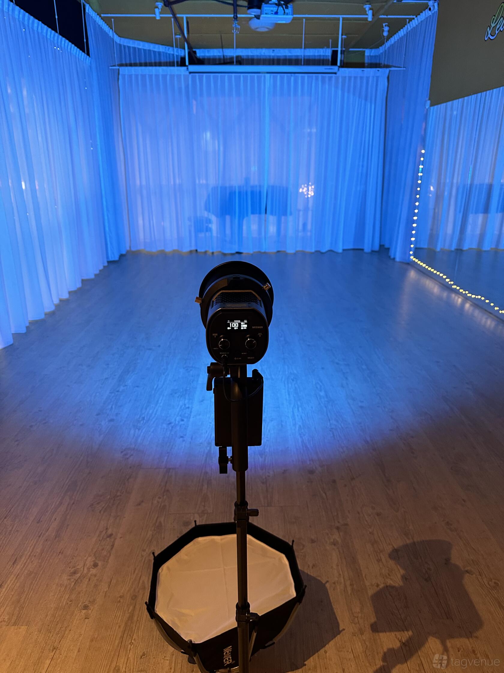 An event space in a dance studio featuring sheer blue curtains, wood floors, and a professional light at Dancing with Friends Singapore.