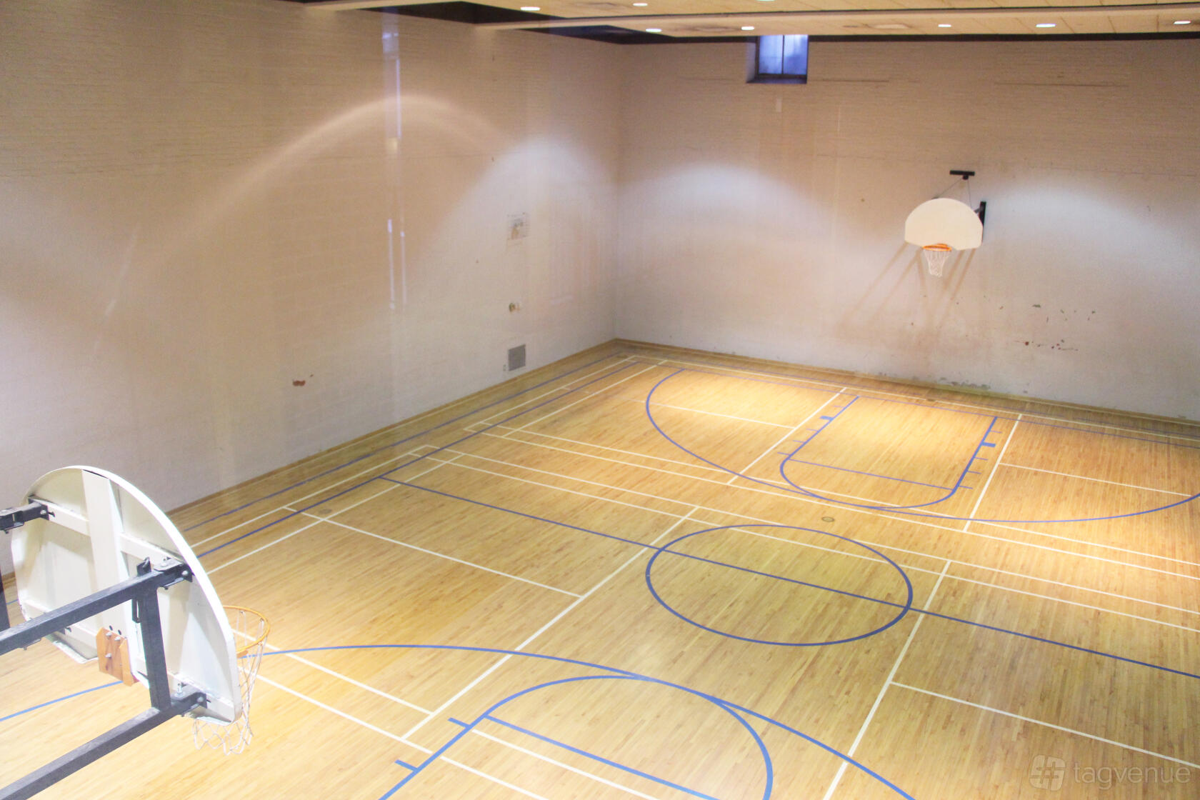 A gymnasium with a polished wooden floor, basketball hoops, and court markings at St. Paul's Bloor Street.