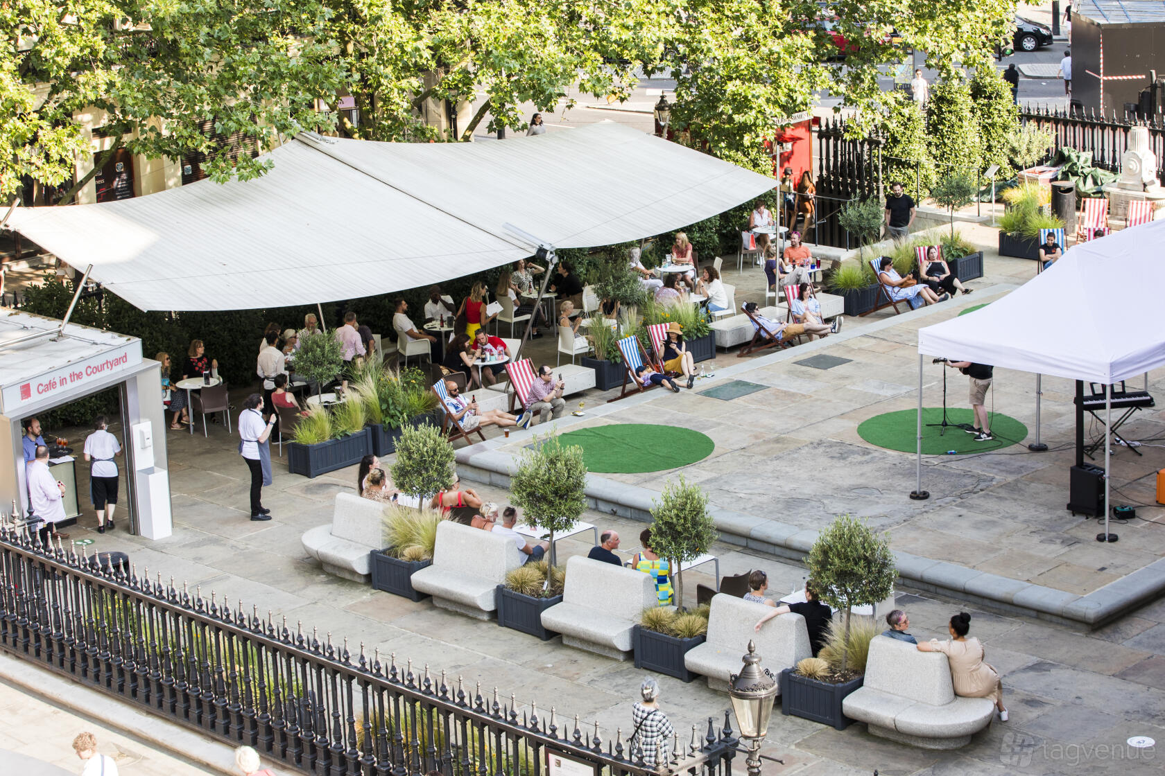 An outdoor courtyard with canopy shade, deck chairs, and potted plants at St Martin-in-the-Field.