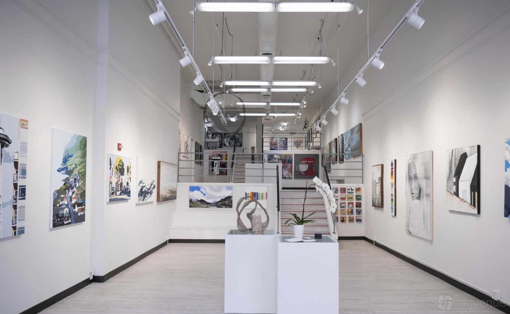 A gallery with white walls, track lighting, and contemporary artworks displayed throughout at Gray Sky Gallery.