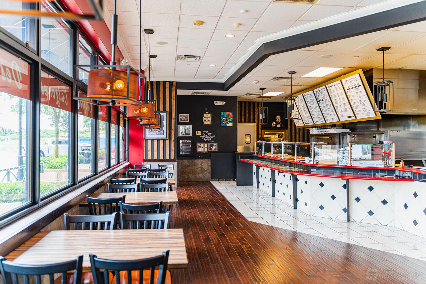 An event space in a restaurant with wood floors, large windows, and menu boards at Mo's Italia Express.