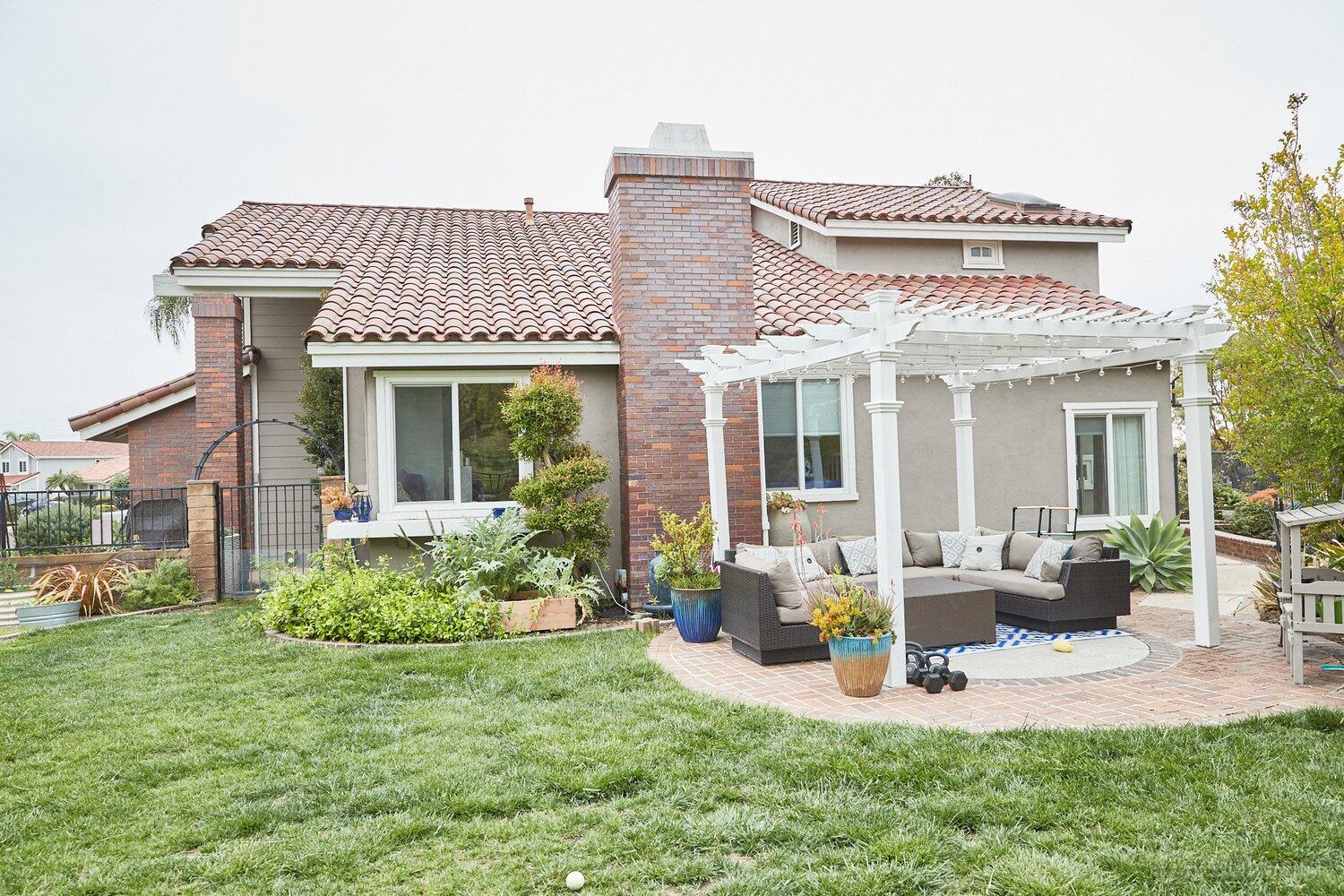 An apartment with a pergola-covered patio, outdoor sectional seating, and landscaped yard at Spacious and Bright 2-Story Home.