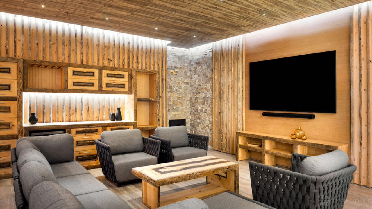 A dining room with wood paneling, stone accent wall, gray cushioned seating, and a mounted TV at World Spa.