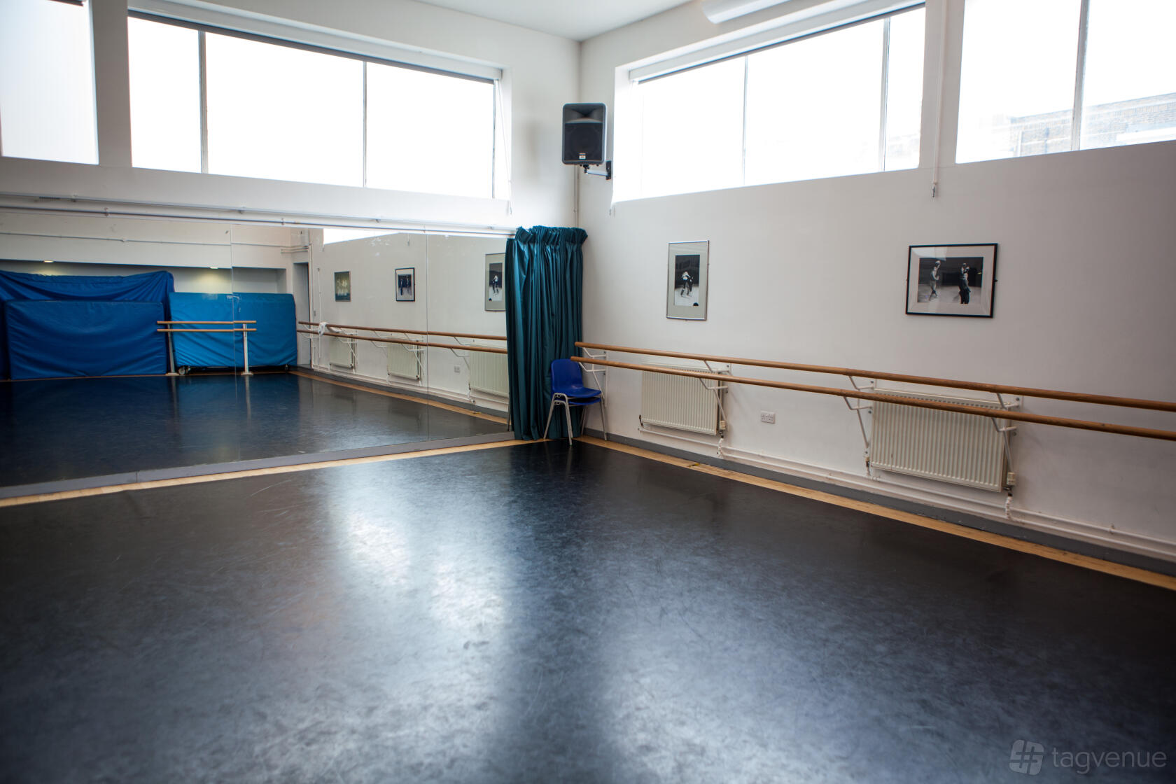 A dance studio with wall-mounted ballet barres, large mirrors, framed photos, and high windows at Wac Arts.
