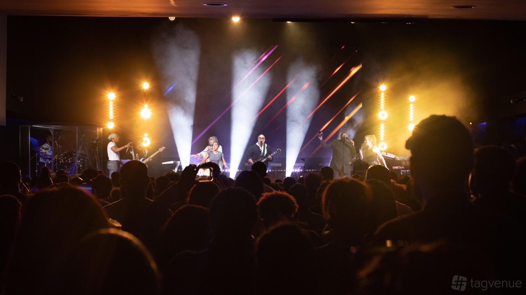 An auditorium with stage lighting, live music performance, and an audience at The Tab Centre.