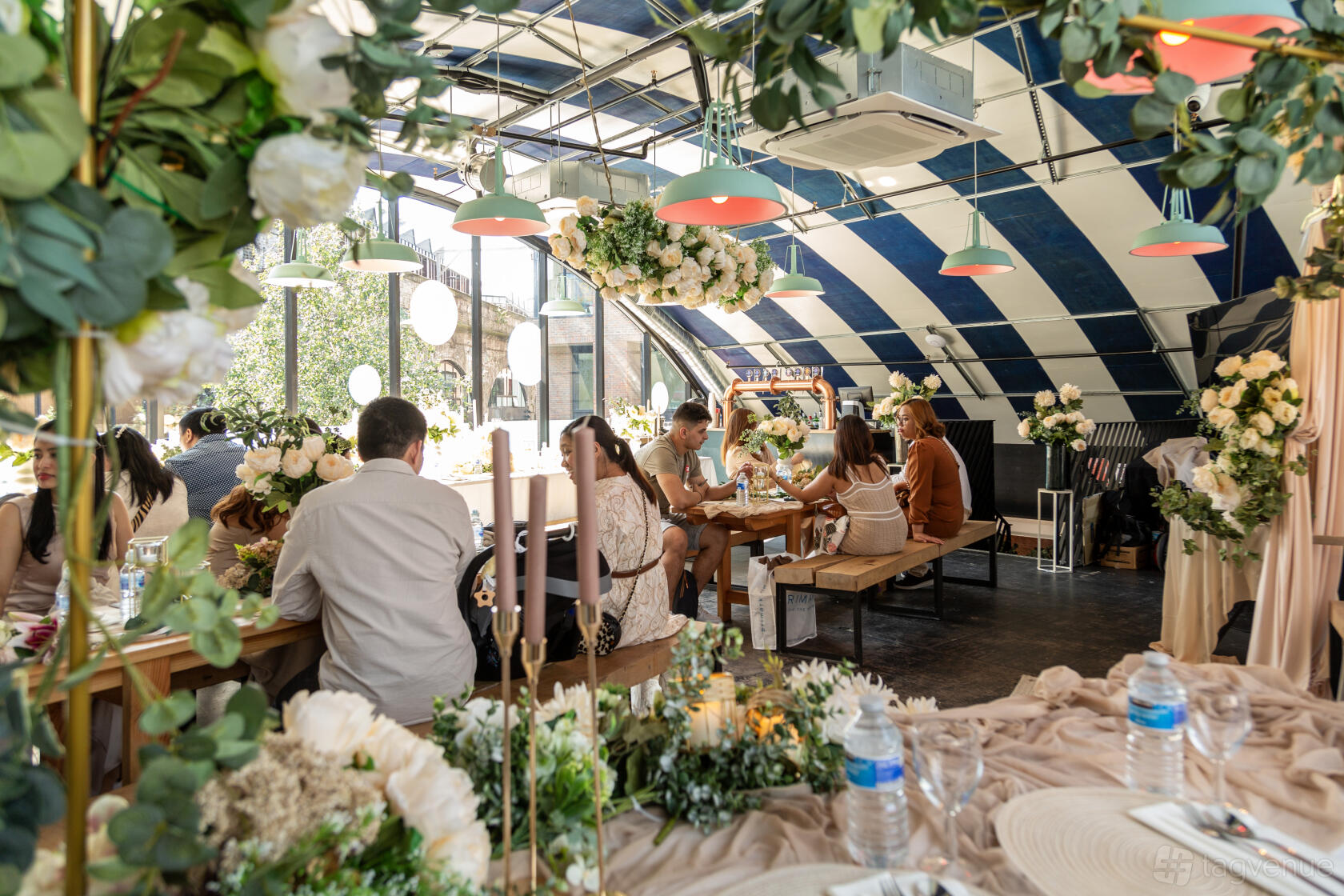 An event space in a brewery with arched striped ceiling, hanging lights, and long banquet tables at 3Locks Industrial Brewery Riverside Views.