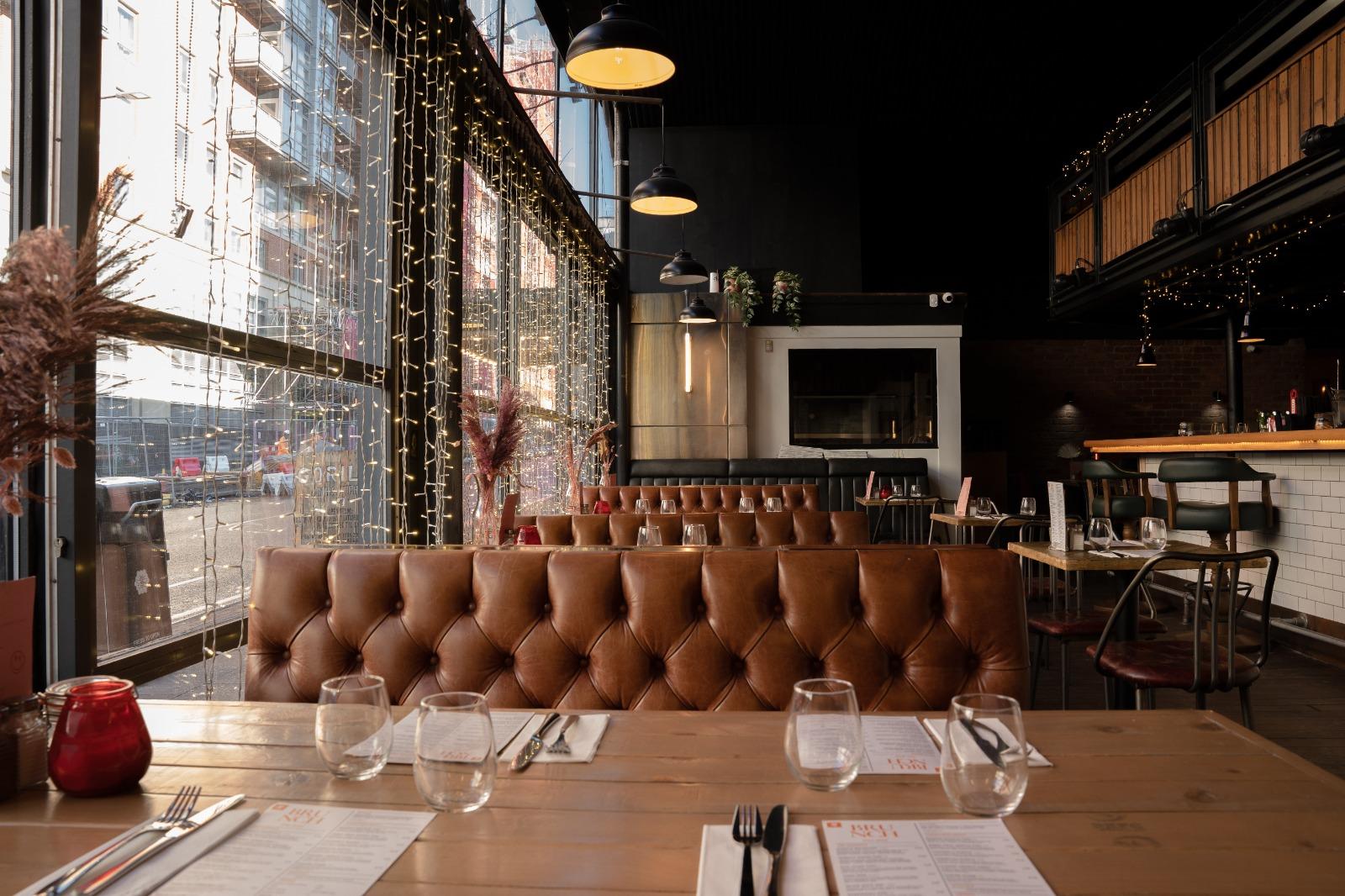 A nightclub with floor-to-ceiling windows, brown leather banquettes, and set dining tables at Gorilla.