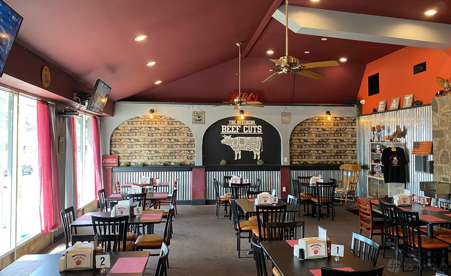 A restaurant with corrugated metal accents, exposed brick mural, and banquet tables at Wilson's Secret Sauce.