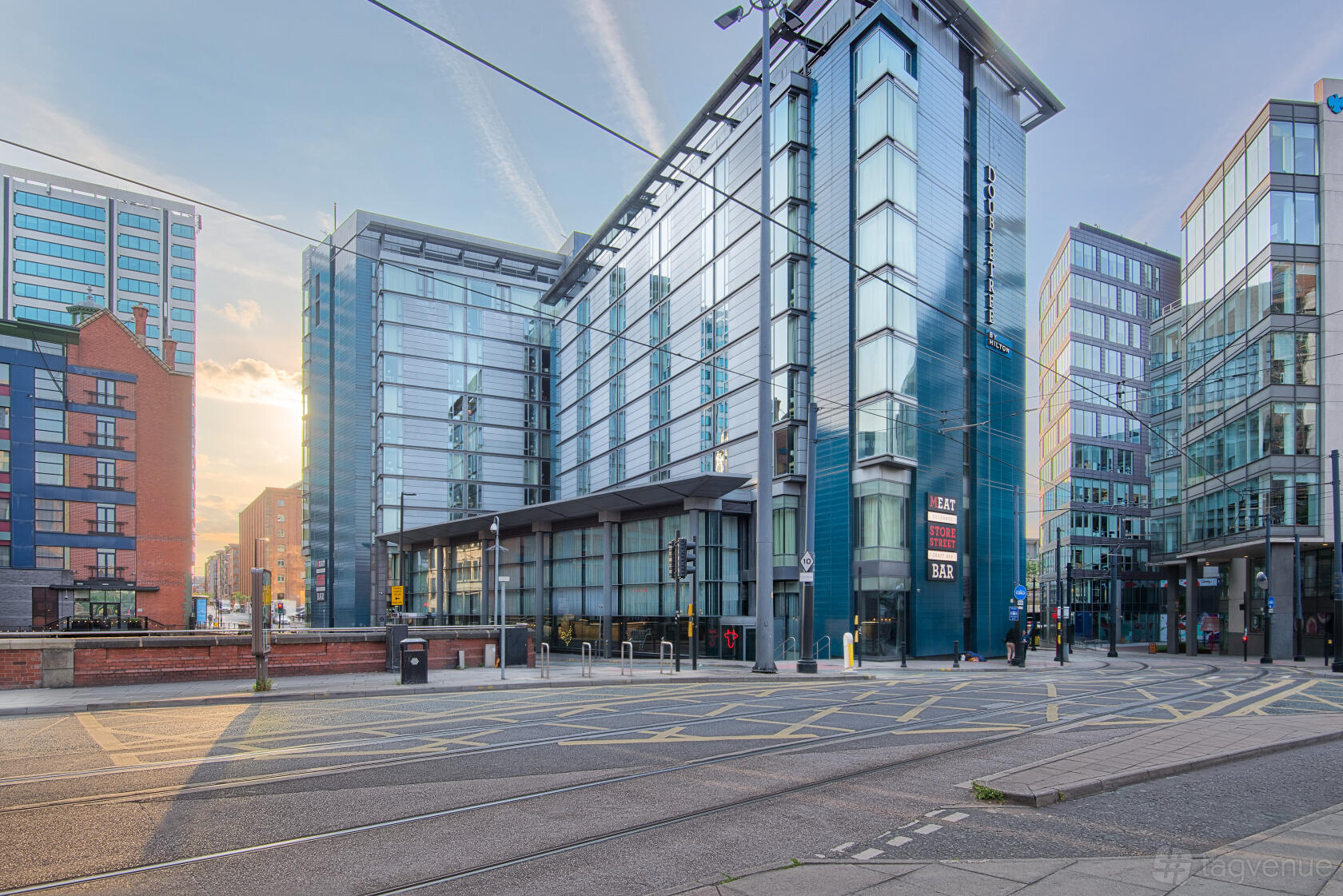A hotel with a glass exterior facade, modern architecture, and a streetcar line at DoubleTree by Hilton Manchester - Piccadilly.