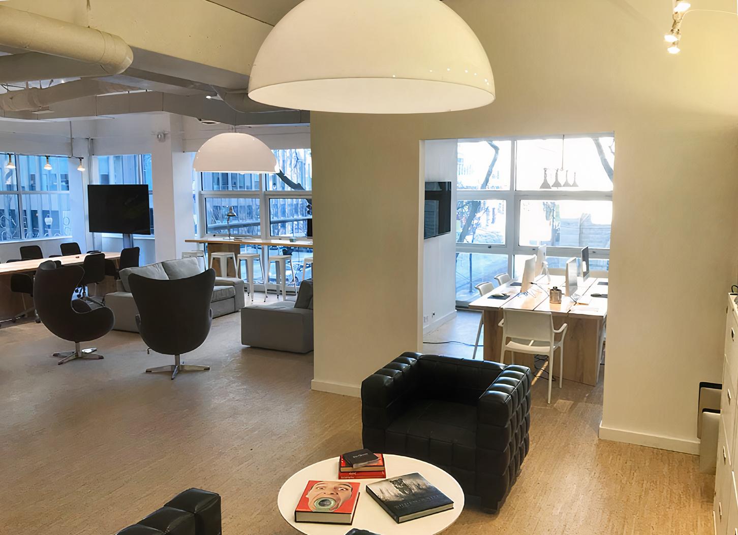 A meeting centre with lounge seating, armchairs, and desks beside large windows at Superior Space.