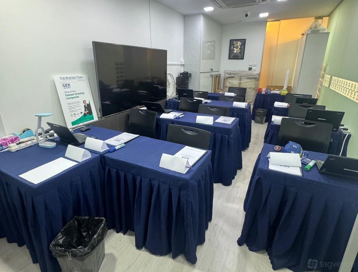 A training room with navy tablecloths, individual workstations, and a large screen at GEX Ventures.